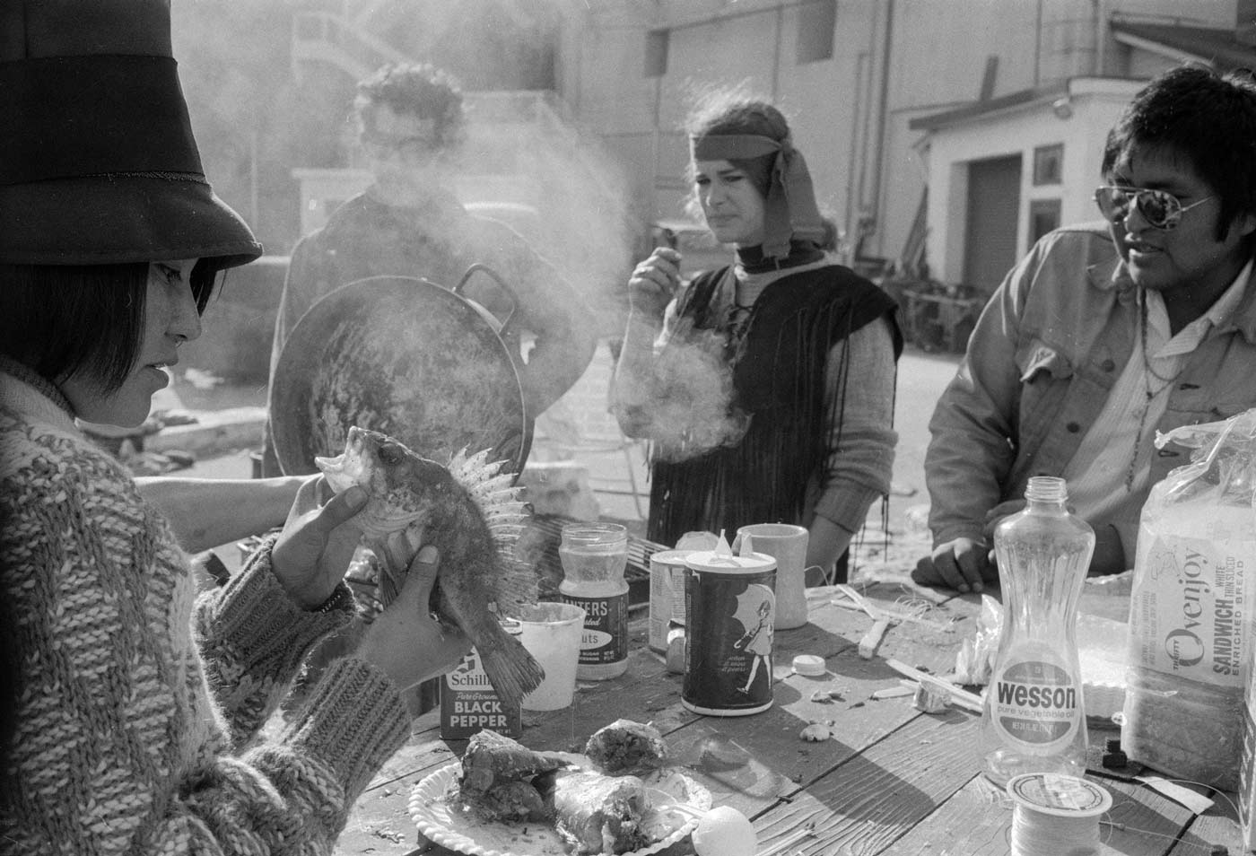 Black and white photograph of AIM members/supporters preparing fish and other food.