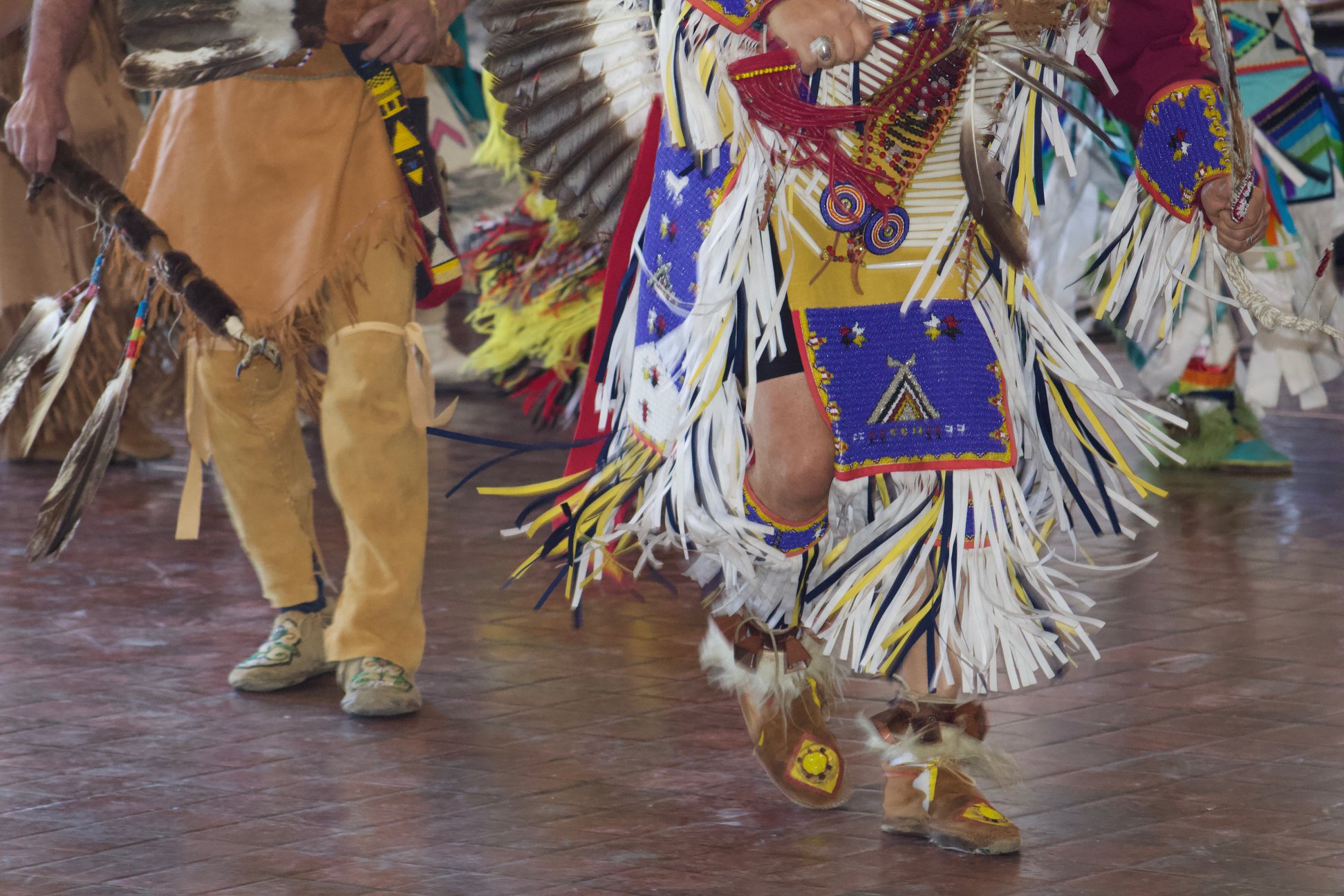 Color photograph showing two male Native American dancers in ceremonial attire in motion at the 2019 American Indian Students Association (AISA) Powwow at William & Mary. Photo by Christian Busch.