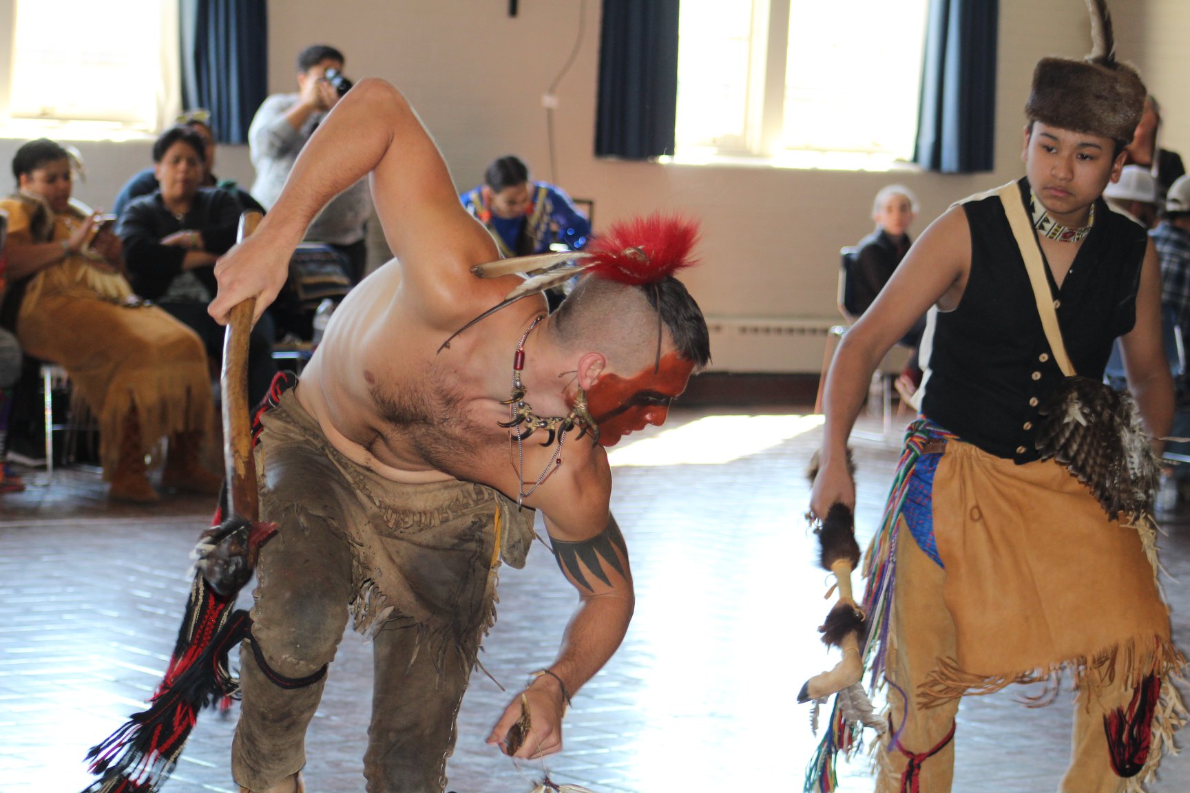 Color photograph showing two male Native American dancers in ceremonial attire in motion at the 2019 American Indian Students Association (AISA) Powwow at William & Mary. Photo by Christian Busch.