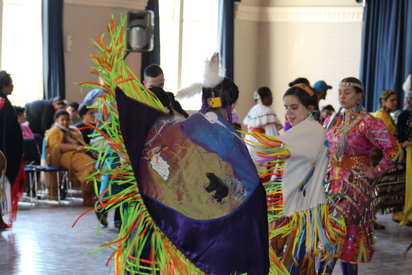 Color photograph showing two male Native American dancers in ceremonial attire in motion at the 2019 American Indian Students Association (AISA) Powwow at William & Mary. Photo by Christian Busch.