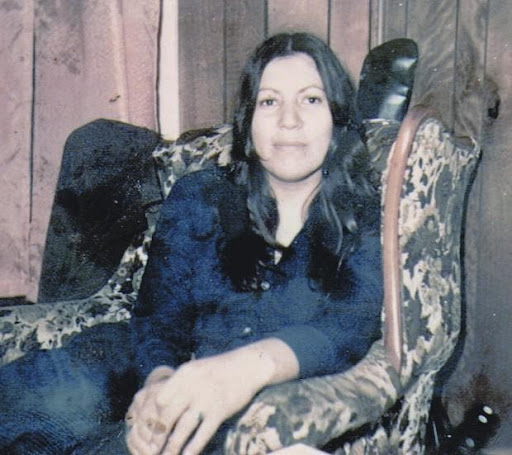 Color photograph of Anna Mae Aquash seated.