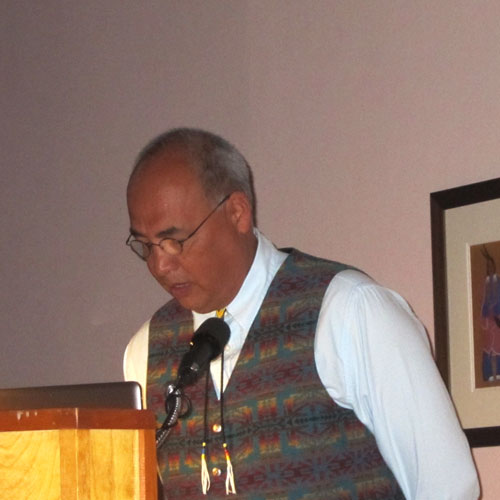 Color photograph of artist Tom Poolaw speaking at the Muscarelle Museum of Art in 2011, during the exhibition In Memory Still: A Kiowa Legacy.