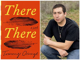 Color image of the cover of the novel There There by author Tommy Orange. The front side shows the title in red with the words in yellow; the title appears on two lines with a black feather under each line; 'A novel' is horizontally printed in black on the center right side; 'Tommy Orange' is printed at the bottom edge. The back cover displays a color photograph of author Tommy Orange, crouching outside and looking out at the camera.